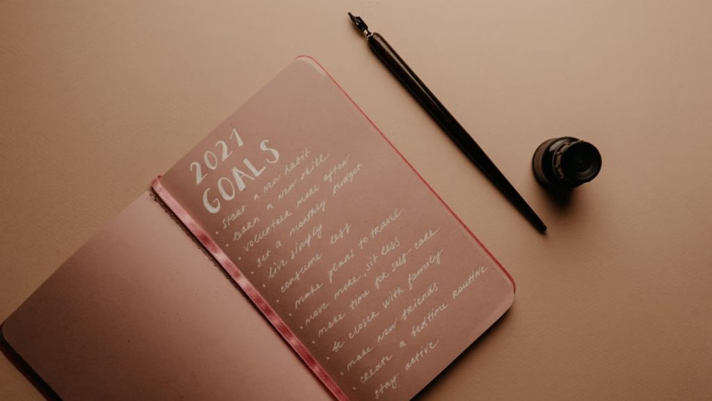A notebook with '2021 Goals' written in calligraphy, featuring a pen and ink bottle.