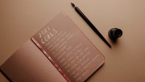 A notebook with '2021 Goals' written in calligraphy, featuring a pen and ink bottle.